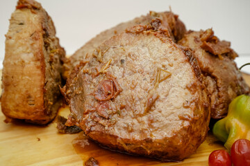 slice of pot cooked meat on wooden board with knife and cutlery.
