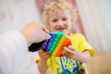 Blond girl playing with pop it sensory toy. A fashionable silicone game for stressed children and...