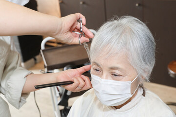 ヘアカットする美容師と高齢者女性