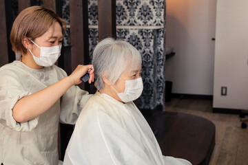 ヘアカットする美容師と高齢者女性
