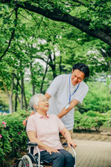 Fototapeta premium 車椅子に乗った高齢者女性と男性スタッフ 