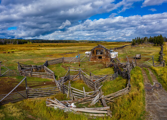 Fototapeta na wymiar Abandoned and decayed old wooden barn, farm facilities and buildings against a stormy sky in Central Interior of British Columbia