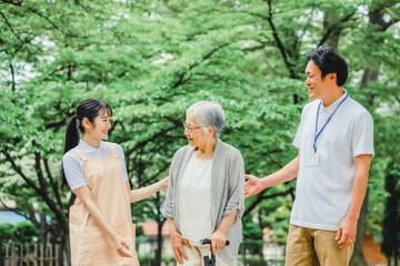 Naklejka premium 高齢者をサポートするエプロン姿の男女（杖） 