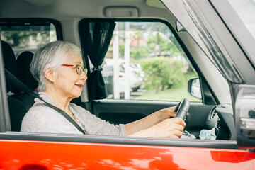 自動車の運転をする高齢者女性（笑顔）
