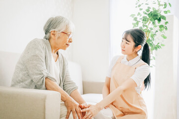 訪問介護・膝をおさえる高齢者女性（心配）
