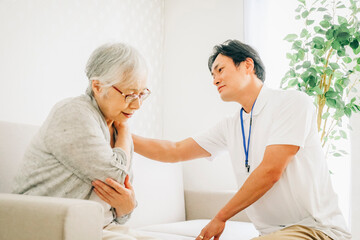 Fototapeta premium 訪問介護する男性と高齢者（肩こり） 