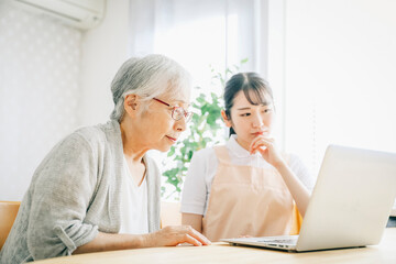 タブレットを使うエプロン姿の女性と高齢者女性
