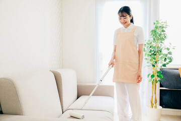 コロコロで部屋を掃除する家政婦（笑顔）
