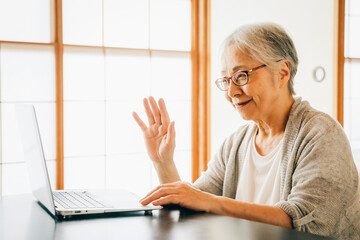 ノートパソコンを使う高齢者女性（笑顔）
