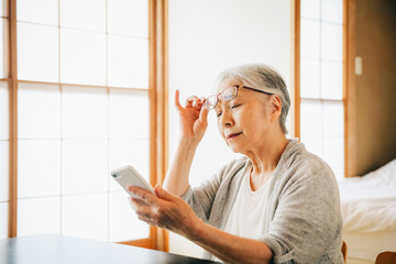 スマホを使う高齢者女性（老眼）
