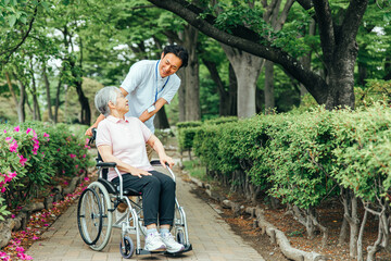 車椅子に乗った高齢者女性と男性スタッフ（全身）
