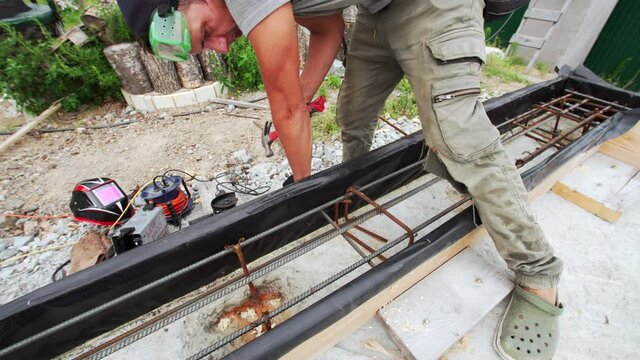 A Worker Is Hammering The Reinfocing Into The Formwork, Temporary Or Permanent Molds Into Which Concrete Or Similar Materials Are Poured. Building Site