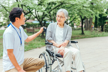 Fototapeta na wymiar 車椅子に乗った高齢者女性と男性スタッフ 