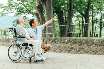 車椅子に乗った高齢者女性と男性スタッフ（全身）
