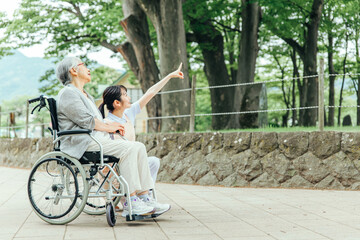 車椅子に乗った高齢者女性と女性スタッフ（全身）
