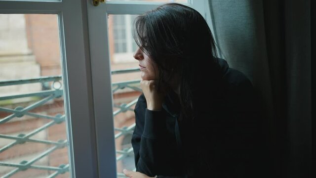 Pensive melancholical woman looking out window thinking