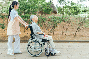 車椅子に乗った高齢者女性と女性スタッフ（横顔）
