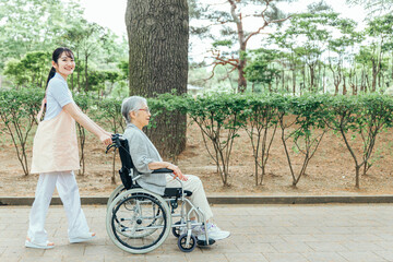 車椅子に乗った高齢者女性と女性スタッフ（横顔）
