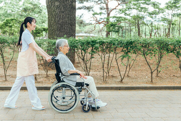 車椅子に乗った高齢者女性と女性スタッフ（横顔）

