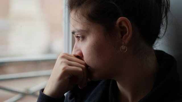 Pensive woman looking outside through window, thoughtful person thinking about life