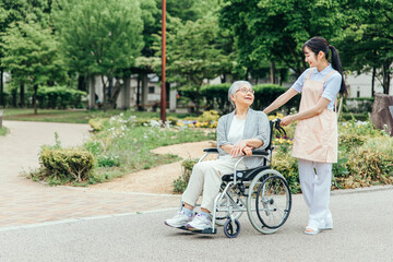 車椅子に乗った高齢者女性と女性スタッフ（花畑）
