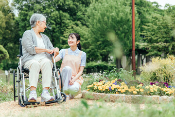 車椅子に乗った高齢者女性と女性スタッフ（花畑）
