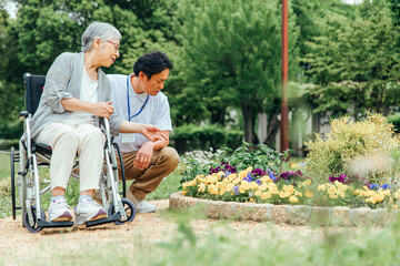 車椅子に乗った高齢者女性と男性スタッフ（花畑）
