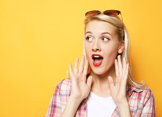 Lifestyle, emotion and people concept: Young surprised woman wearing casual over yellow background