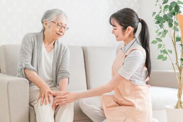 訪問介護・膝をおさえる高齢者女性
