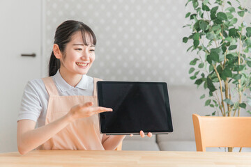 タブレットPCで説明するエプロン姿の女性
