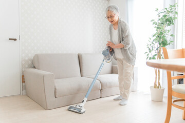 部屋を掃除する高齢者女性（笑顔）
