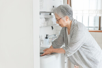 洗濯機を使う高齢者女性
