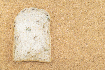Whole wheat bread slices have rice grain on wood background.