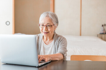 ノートパソコンを使う高齢者女性（笑顔）
