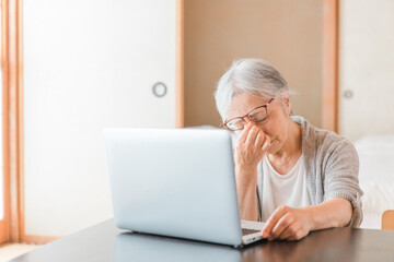 Fototapeta na wymiar ノートパソコンを使う高齢者女性（眼精疲労・頭痛） 