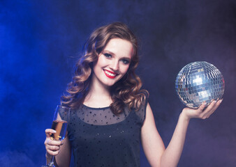 Naklejka premium Woman holding a glass of wine and disco ball, she is smiling.