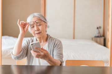 スマホを使う高齢者女性（老眼）
