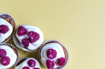 Cupcakes with white cream and berries on a yellow background top view. Sweet cupcakes on a colored background are a place for text.