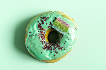 Donut with green icing on a green background close-up. Fresh donut with icing on a light background