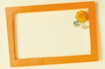 A colored frame decorated with yellow flowers on a light background of the mine space. Flat ley bright orange frame and yellow flower decor	