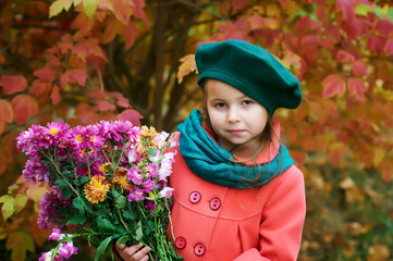 Portrait of a little girl in an autumn coat and beret in the forest