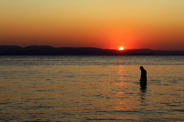 Fototapeta premium At sunset, a man goes to sea for a swim.