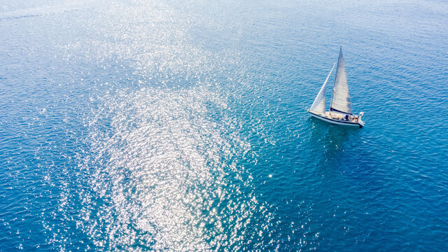 Drone aerial view of a sailing boat on a blue ocean sea waters.