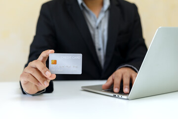 Close up credit card in hand of businessman using laptop,  purchase and payment concept.