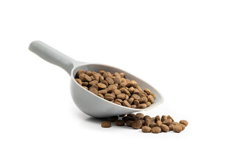 Kibbles in measuring cup and some random pieces. 1 cup dry pet food portioned out a medium to large dog. Brown small oval pebbles. Isolated on white. Selective focus.
