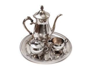 Isolated Ornate 4-piece tea set on table. Perspective view. Silver or silver plated tea pot, sugar bowl and cream or milk jug. Ornamental silverware to serve hot tea or coffee. Selective focus.
