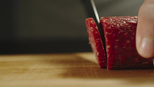 SLOW MOTION: Man Slicing A Piece Of Salami Suasage On Cutting Board