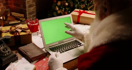Bearded Santa Claus having a video chat using laptop computer with green chroma key screen. St Nicholas talking to kids on web - christmas spirit magic, technology 4k footage