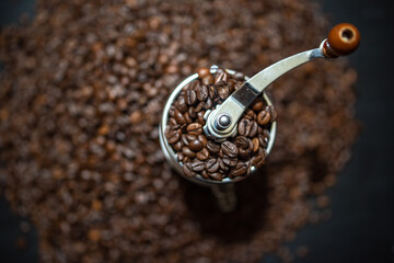 Manual mechanical coffee grinder and a pile of coffee beans.