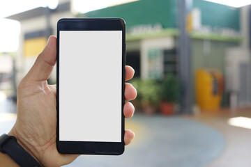 Adult hand holding a smartphone outside a store with blank copy space screen for text message or information content